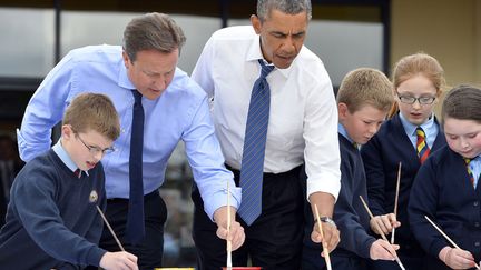 Le pr&eacute;sident am&eacute;ricain Barack Obama (D) et le Premier ministre britannique David Cameron (G) font de la peinture avec des enfants lors d'une visite conjointe d'une &eacute;cole primaire &agrave; Enniskillen (Irlande du Nord), le 17 juin 2013. (JEWEL SAMAD / AFP)