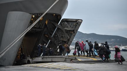 Un groupe de réfugiés entre dans le navire de guerre affrété par la marine grecque dans la port de Mytilène, sur l'île de Lesbos. (LOUISA GOULIAMAKI / AFP)