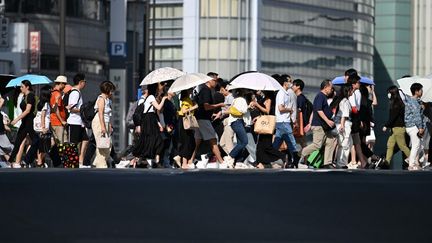 Des passants dans les rues de Tokyo (Japon) se protègent du soleil avec des ombrelles, lors d'une journée de fortes chaleurs, le 29 juillet 2024. (YOSHITAKA NISHI / YOMIURI / AFP)