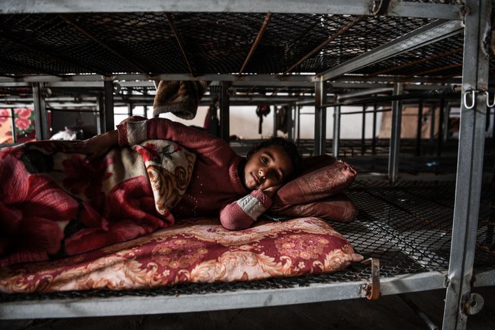 A child rests on a makeshift bed installed in a poultry farm in Rafah (Gaza Strip), February 7, 2024. (ABED ZAGOUT / ANADOLU / AFP)