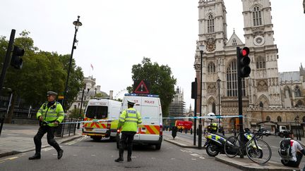 Des policiers établissent un cordon de sécurité autour du Parlement britannique, à Londres, sur les grilles duquel une voiture a foncé, le 14 août 2018. (HANNAH MCKAY / REUTERS)