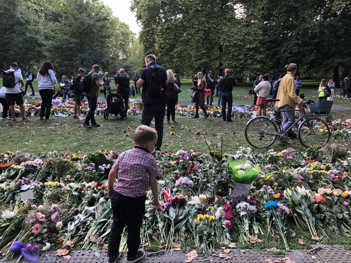 Un petit garçon regarde les fleurs déposées à Green Park, près de Buckingham Palace, à Londres, le 10 septembre 2022.&nbsp; (MARIE-ADELAIDE SCIGACZ / FRANCEINFO)