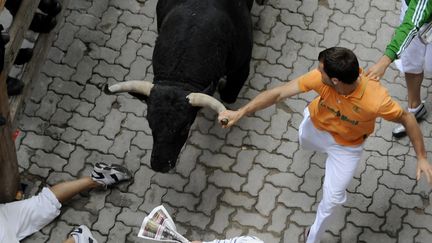 Des hommes courent &agrave; c&ocirc;t&eacute; de taureaux, mercredi 11 juillet, lors des&nbsp;f&ecirc;tes de la San Fermin, &agrave; Pampelune (Espagne). (ANDER GILLENEA / AFP)