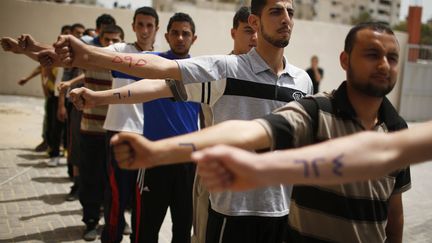 Des volontaires posent avec leur num&eacute;ros d'enregistrement marqu&eacute; sur 'avant-bras lors d'une session de recruitement du Hamas &agrave; Gaza City (Palestine), le 3 juin 2013. (MOHAMMED SALEM / REUTERS)