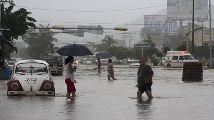 Des habitants d'Acapulco (Mexique) marchent dans les rues inond&eacute;es de la ville, le 15 septembre 2013. Un ouragan et une temp&ecirc;te tropicale se dirigent vers le Mexique. (JACOBO GARCIA / REUTERS)