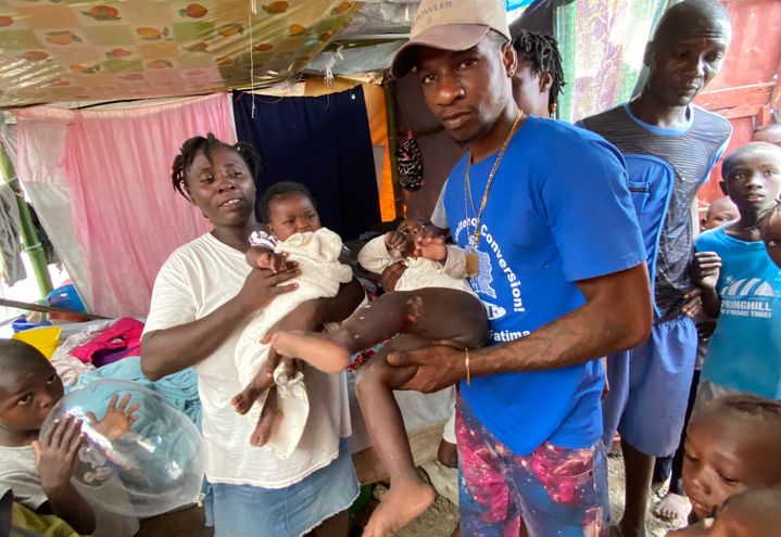 Brunette et son bébé, dans l'abi de fortune où elle s'est réfugiée avec sa famille, aux Cayes, après le tremblement de terre à Haïti du 14 août 2021. Au centre, un homme montre les blessures de son fils. (BORIS LOUMAGNE / RADIO FRANCE)