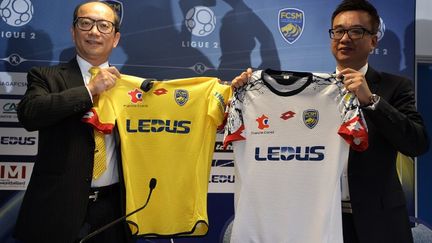 Les dirigeants de Ledus, Li Wing Sang et Chi Hung Chiu, posent avec les nouveaux maillots du FC Sochaux-Montb&eacute;liard, le 6 juillet 2015, &agrave; Sochaux (Doubs). (PATRICK HERTZOG / AFP)