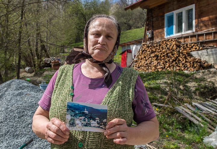 Valeria, une habitante de Geamana, montre une photo du village avant qu'il ne soit englouti par les déchets miniers. (MARIE-ADELAÏDE SCIGACZ / FRANCEINFO)