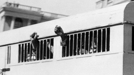 les huit accusés, dont Nelson Mandela, quittent, poings levés, le palais de justice de Pretoria, à  la fin du procès de Rivonia (octobre 1963/juin 1964).
 
Mandela, qui purgeait déjà sa peine de prison, ainsi que Sisulu, Mbeki, Motsoaledi, Mlangeni, et Goldberg, sont condamnés devant la haute cour du Transvaal à la réclusion à perpétuité sur l'île-bagne de Robben Island, au large du Cap. (AFP)