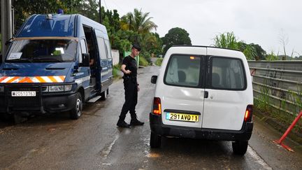 Un gendarme barre la route aux habitants de Petit-Bourg (Guadeloupe), le 30 juin 2013, apr&egrave;s un drame familial s'&eacute;tant sold&eacute; par la mort de six personnes. (EDDY NEDELKOVSKI / AFP)