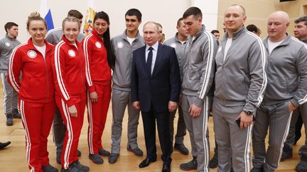 Le président russe Vladimir Poutine pose avec des athlètes russes qui participent aux JO d'hiver&nbsp;de 2018 à Pyeongchang. (GRIGORY DUKOR / POOL / REUTERS POOL)