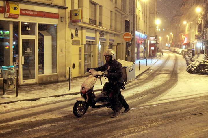 Un homme pousse son scooter dans une rue enneig&eacute;e de Paris, le 18 janvier 2013.&nbsp; (MAXPPP)