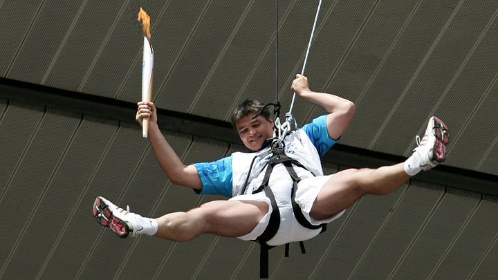 L'ancien judoka David Douillet descendant en rappel du Stade de France avec la flamme olympique, le 25 juin 2004. (JEAN-PIERRE MULLER / AFP)