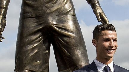 La photo de Cristiano Ronaldo, souriant, au côté de sa statue. (GREGORIO CUNHA / AFP)