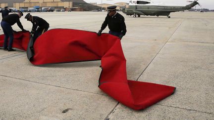 Des militaires am&eacute;ricains tentent de replacer le tapis rouge soulev&eacute; par le vent alors que l'h&eacute;licopt&egrave;re Marine One transportant le pr&eacute;sident Barack Obama vient de se poser sur l'Andrew air force base pr&egrave;s de Washington (Etats-Unis), le 10 f&eacute;vrier 2014. (LARRY DOWNING / REUTERS)