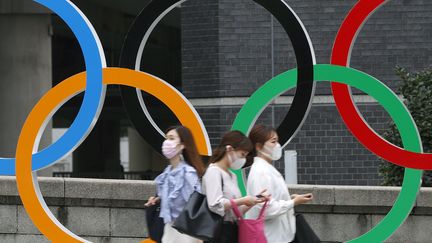 Des femmes devant les anneaux olympiques à Tokyo (Japon), jeudi 8 juillet 2021. (SHINJI KITA / KYODO NEWS / AFP)