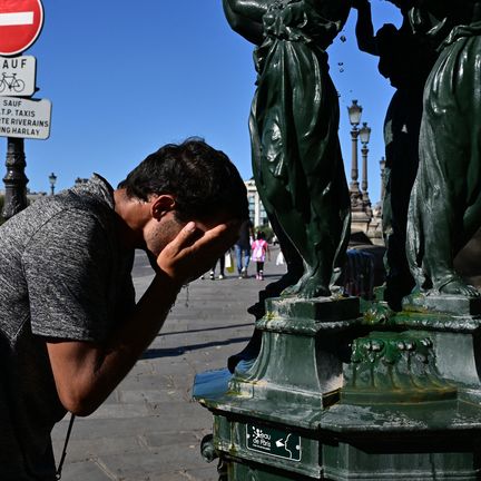 A man cools off in a public fountain during a heat wave on August 21, 2023 in Paris.  (MIGUEL MEDINA / AFP)