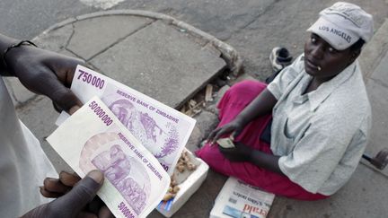 Un Zimbabwéen tient un billet de 50 millions de dollars dans une rue de la capitale Harare. En 2008, l'inflation avait atteint le&nbsp;taux astronomique de 100.000 %. (MIKE HUTCHINGS / X00388)