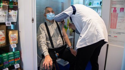 Un patient reçoit une injection du vaccin AstraZeneca, le 12 mars 2021, dans une pharmacie à Paris. (MARTIN BUREAU / AFP)