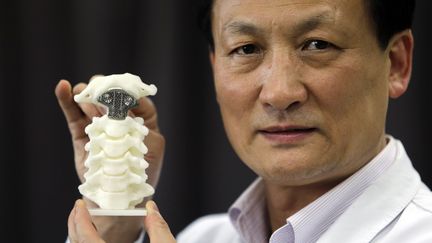 Le professeur&nbsp;Liu Zhongjun avec la premi&egrave;re vert&egrave;bre imprim&eacute;e en 3D et implant&eacute;e sur un patient souffrant d'un cancer des os, le 21 ao&ucirc;t 2014 &agrave; la Peking&nbsp;University Third Hospital de P&eacute;kin (Chine). ( JASON LEE / REUTERS)