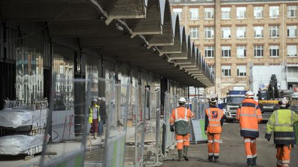 Des ouvriers&nbsp;longent un chantier à Paris, le 18 octobre 2016. (LIONEL BONAVENTURE / AFP)