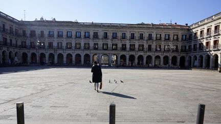 Une femme traverse une place déserte à Vitoria (Espagne), le 14 mars 2020, en pleine épidémie du coronavirus Covid-19. (VINCENT WEST / REUTERS)