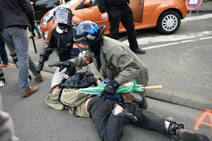 Le policier à droite tient son LBD à la main, et l'arme est cette fois pointée vers le sol devant lui. (MAXPPP)