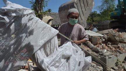 Un homme s'active pour évacuer les décombres après le séisme à Lombok (Indonésie), le 12 août 2018. (ADEK BERRY / AFP)