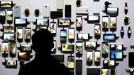 Un&nbsp;homme&nbsp;devant&nbsp;une série d'appareils de la firme Google, fonctionnant sous le système d'exploitation Android, le 29 septembre 2015 à San Francisco (Californie). (JUSTIN SULLIVAN / AFP)