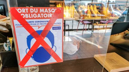 Un panneau rappelant l'obligation du port du masque en intérieur est barré à l'intérieur d'une boulangerie de Valence (Drôme), le 19 mars 2022. (NICOLAS GUYONNET / HANS LUCAS / AFP)