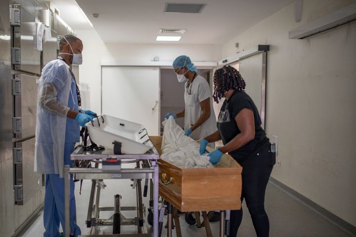 2 septembre 2021. Dans la morgue du CHU de Martinique, deux agents d'amphithéatre aident Chewyl, assistante funéraire, à déposer le corps d un patient décédé du Covid-19, dans un cercueil.&nbsp; (FANNY FONTAN / HANS LUCAS / AFP)