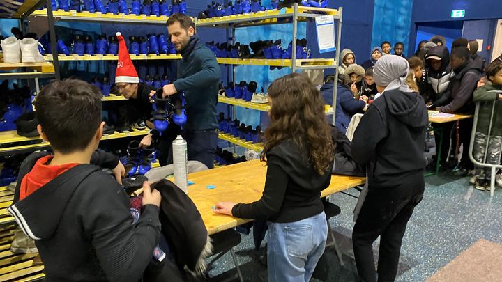 Des enfants récupèrent des patins à la patinoire éphémère de Trappes (Yvelines), en décembre 2022. (LAURIANE DELANOE / FRANCEINFO)