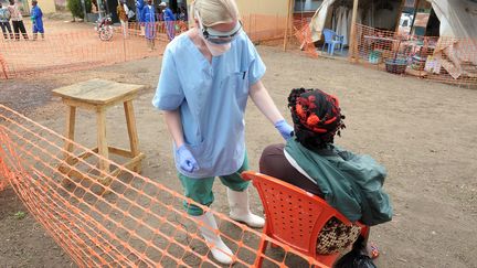 Une infirmi&egrave;re de l'ONG "M&eacute;decins sans fronti&egrave;res" examine une patiente dans un centre pour les victimes du virus Ebola &agrave; Guekedou (Guin&eacute;e), le 1er avril 2014. (SEYLLOU / AFP)