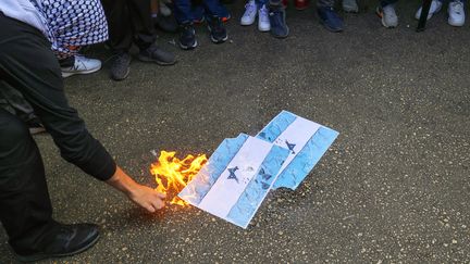 Des étudiants à Beyrouth brûlent des drapeaux israéliens lors d'un rassemblement de soutien aux Palestiniens devant l'université, le 9 octobre 2023. (ANWAR AMRO / AFP)