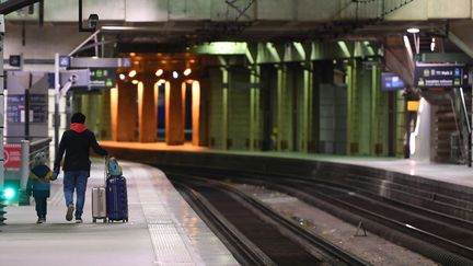 Un passager accompagné d'un enfant, gare Montparnasse à Paris, le 11 décembre 2019. (ALAIN JOCARD / AFP)