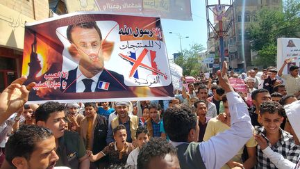 Des manifestants brandissent une affiche avec le visage d'Emmanuel Macron grimé en cochon, après&nbsp;ses déclarations défendant le droit à la caricature au nom de la liberté d'expression,&nbsp;le 31 octobre à Taez (Yémen). (AFP)