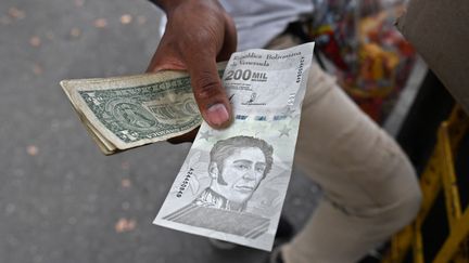 Un homme montre un nouveau billet de bolivar, à Caracas, le 14 avril 2021. (FEDERICO PARRA / AFP)