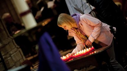 Une jeune fille allume une bougie lors de la c&eacute;r&eacute;monie d'hommage aux 28 personnes, dont 22 enfants, tu&eacute;es dans l'accident de car survenu en Suisse, le 14 mars 2012 &agrave; Louvain (Belgique). (CHRISTOPHE KETELS / BELGA MAG)