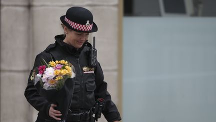 Une&nbsp;policière dépose un bouquet de fleurs près du London Bridge, le 4 juin 2017, au lendemain de l'attentat de Londres. (DANIEL LEAL-OLIVAS / AFP)