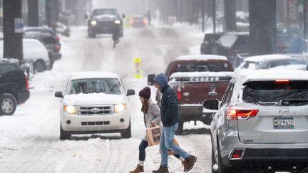 Des piétons traversent une chaussée enneigée à Greenville (Caroline du Sud), le 16 janvier 2022. (SEAN RAYFORD / GETTY IMAGES NORTH AMERICA / AFP)