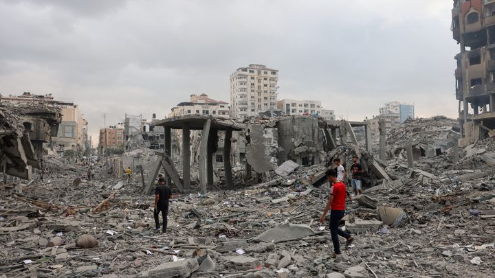 Des Palestiniens marchent parmi les décombres d'immeubles, après des frappes israéliennes, le 10 octobre 2023, à Gaza. (MOHAMMED ABED / AFP)