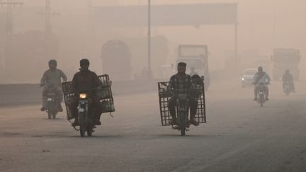 Des habitants circulent dans le brouillard de pollution de Lahore, le 2 novembre 2024 au Pakistan. (ARIF ALI / AFP)