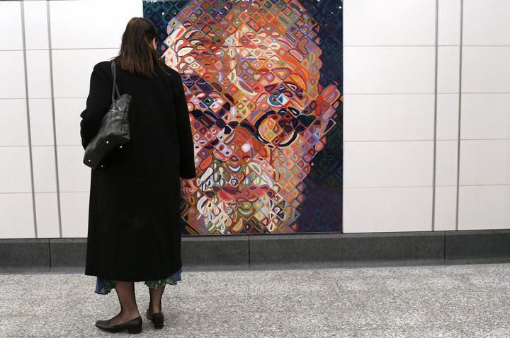 Une femme observe l'auto-portrait en mosaïque de l'artiste Chuck Close dans une station de metro new-yorkaise, le 1er janvier 2017. (YANA PASKOVA / GETTY IMAGES NORTH AMERICA)