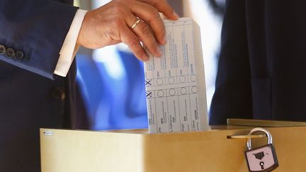 Le candidat de la CDU, Amin Laschet, vote en pliant son bulletin à l'envers, à Aix-la-Chapelle, en Allemagne, lors des élections législatives, dimanche 26 septembre 2021. (FRANCK FIFE / AFP)