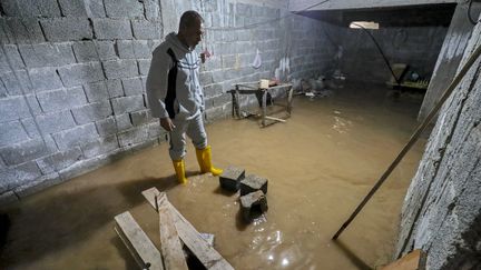 Un homme observe l'inondation de sa cave dans la ville de Zliten, une ville côtière de Libye, le 13 février 2024. (MAHMUD TURKIA / AFP)