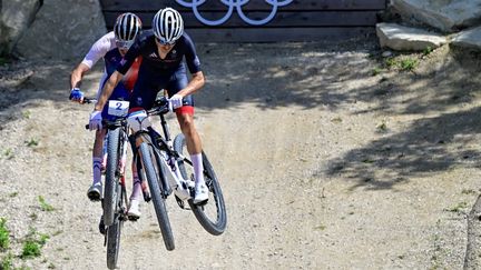 Au terme d'un duel musclé avec Tom Pidcock (en bleu) dans le dernier tour de la course de VTT cross-country aux Jeux olympiques de Paris 2024, lundi 29 juillet 2024 à Elancourt (Yvelines), le Français Victor Koretzky a pris la médaille d'argent derrière le grandissime favori britannique. (JOHN MACDOUGALL / AFP)