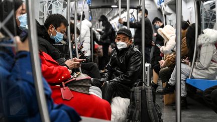 Des personnes portent des masques contre le Covid-19 dans un métro à Pékin, le 19 décembre 2022. (NOEL CELIS / AFP)