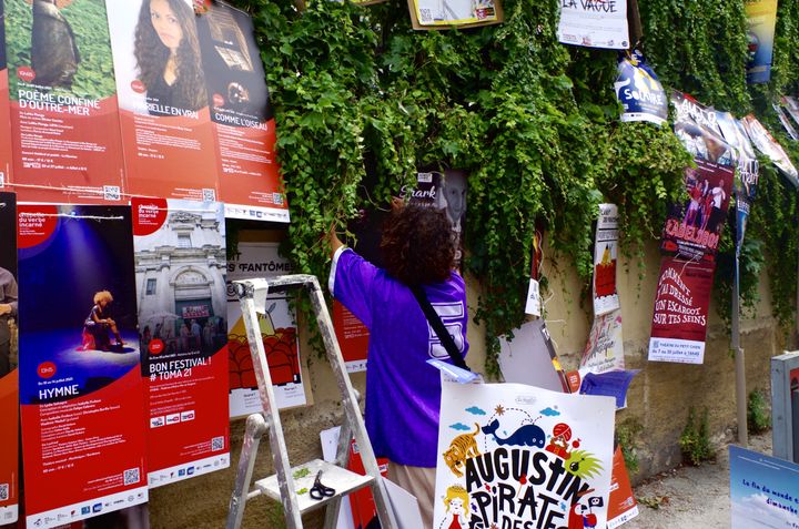 MJ, jeune Lyonnais, accroche des affiches sur un mur, à Avignon, le 6 juillet 2021. (JEREMIE LAURENT-KAYSEN)