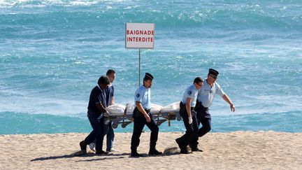 Les gendarmes portent le corps de l'homme tu&eacute; par un requin, le 8 mai 2013, &agrave; Saint-Gilles (La R&eacute;union). (RICHARD BOUHET / AFP)