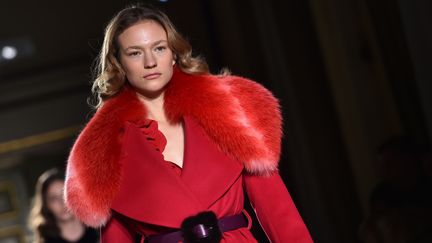 Chez Blumarine, ce sont des demoiselles romantiques, qui s'avancent vêtues de robes sinueuses. Les décolletés des pulls, robes et manteaux sont évasés et bordés de vison coloré. Les mises à volants ou en satin soyeux enveloppent le corps. Les fleurs sont partout. En broderies ou paillettes jaune d'or comme le mimosa sur des robes à sequins étincelantes. Des pivoines rouges sont appliquées sur une fourrure. D'autres guirlandes fleuries enlacent la taille d'un habit sombre ou grimpent le long d'un bras sur un tricot noir.
 (GIUSEPPE CACACE / AFP)